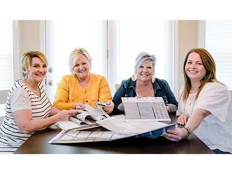 Four women sitting at a table holding fabric samples